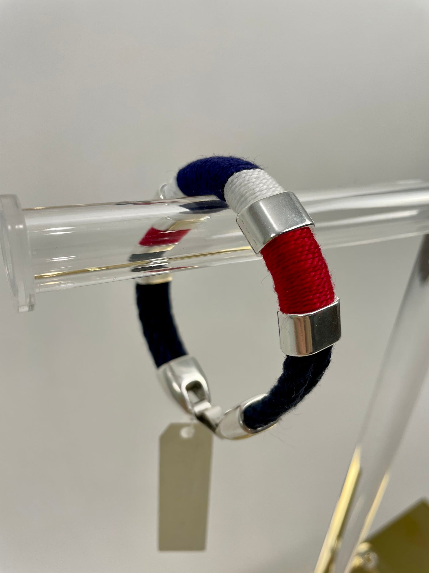 Navy blue, red, and white make up the pattern of this handmade rope bracelet with silver metallic accents and clasp to create a classic New England coastal bracelet.